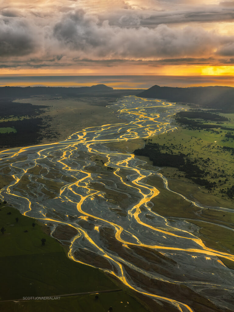 Braided river channels glowing gold from the air, New Zealand, aerial photograph by Scott Jon