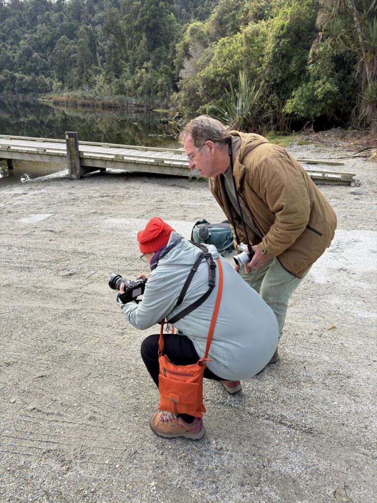 A workshop guest lining up a shot by a West Coast lake with a little help