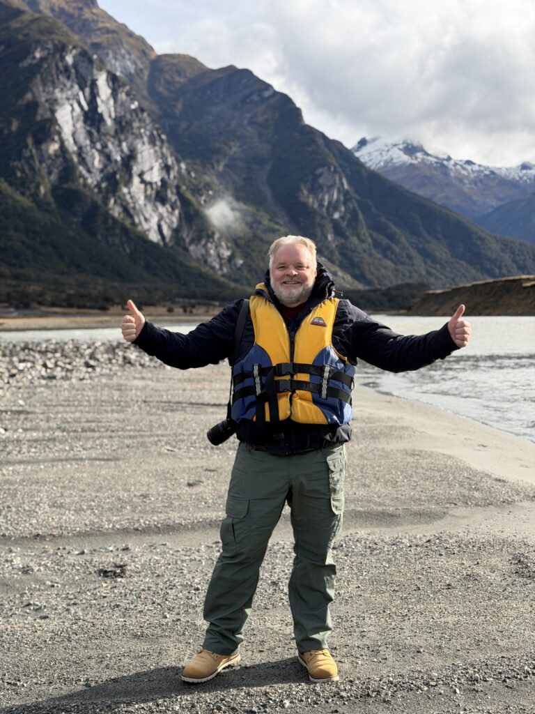 A guest giving two thumbs up on a South Island river beach
