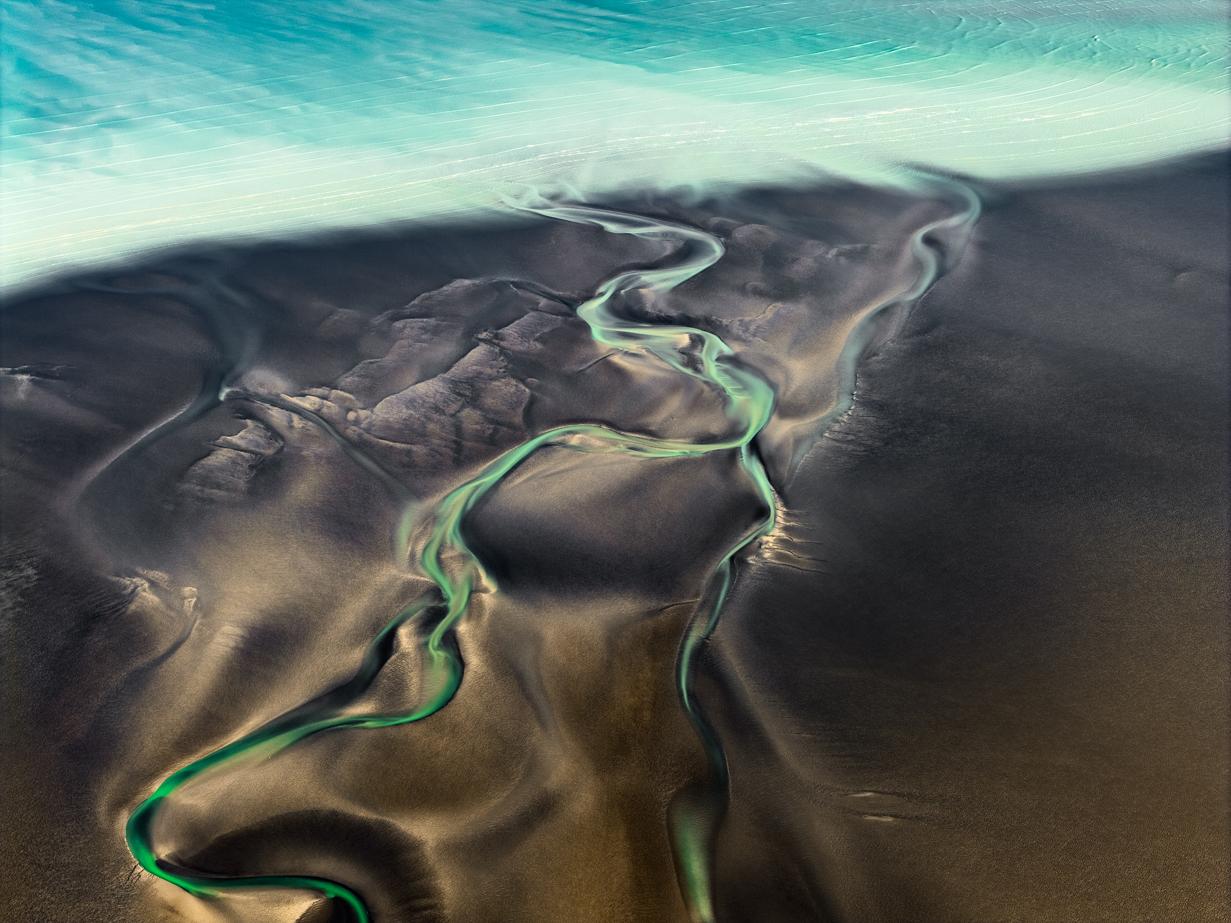 Turquoise water and winding green tidal channels across dark Kimberley mudflats near Broome, aerial photograph by Scott Jon